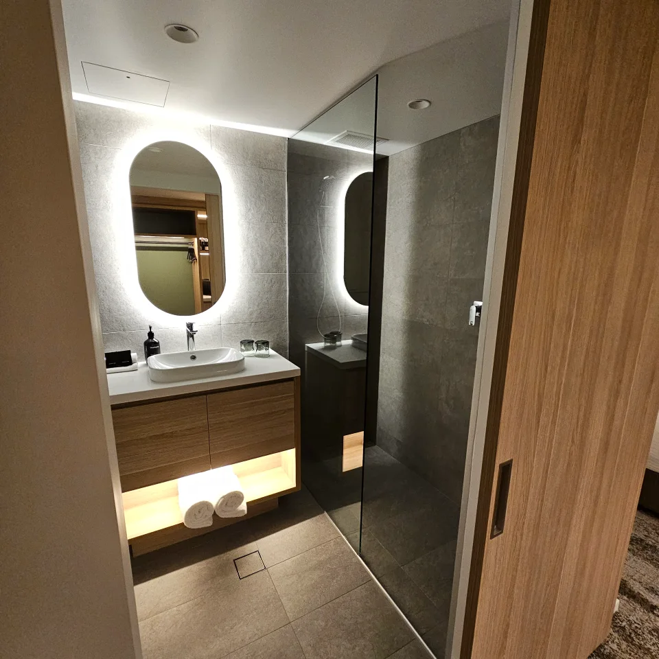 Bathroom with backlit oval mirror, timber vanity and walk-in rain shower
